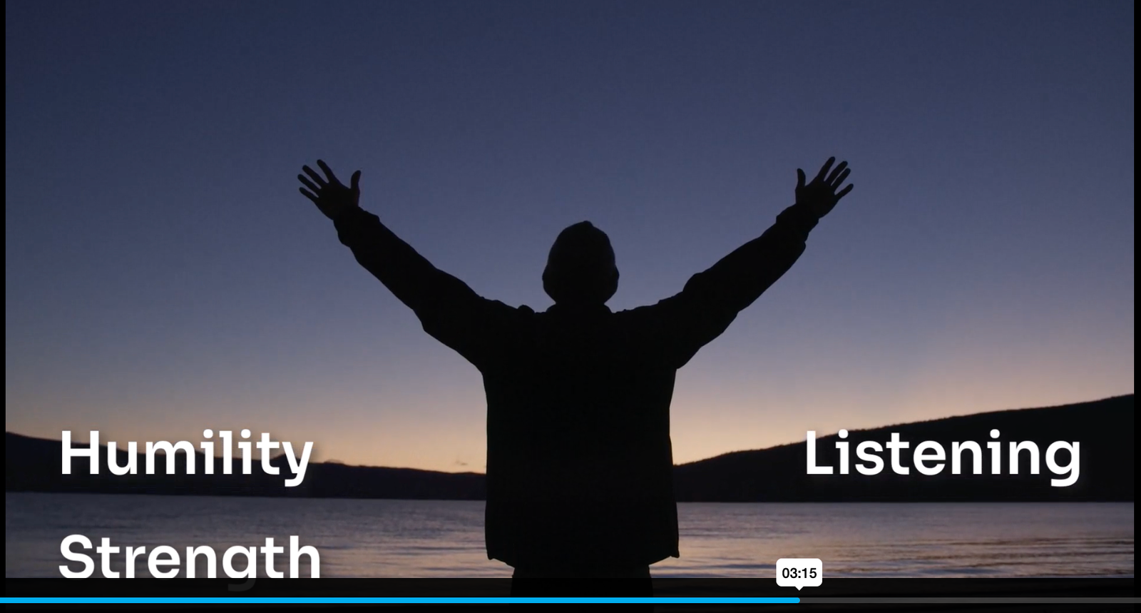 Still from one of the companion videos — a man in silhouette against a dusk sky, arms raised at the edge of a lake, with the words Humility, Strength, and Listening overlaid.